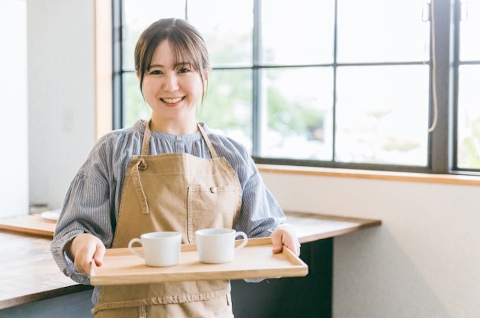 笑顔でコーヒーを運ぶ女性