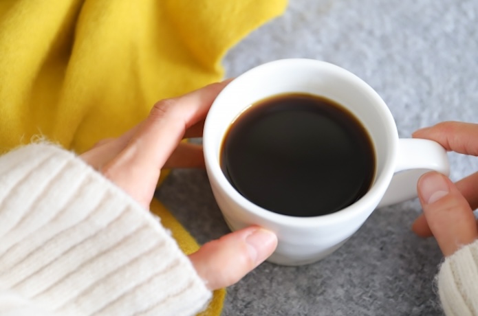 コーヒーを持つ女性の手元