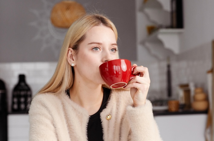 赤いカップでコーヒーを飲む女性