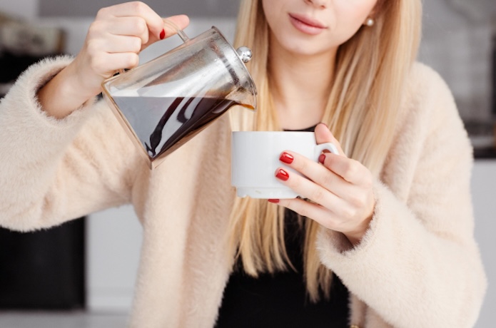 マグカップにコーヒーを注ぐ女性